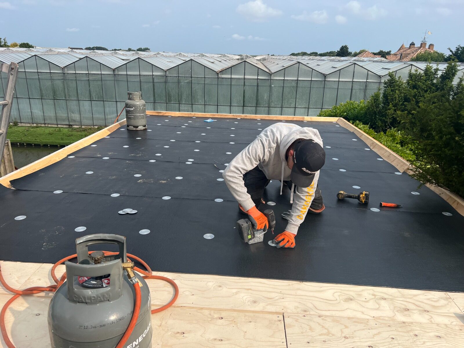 Flat roof in Westland — worker by greenhouses